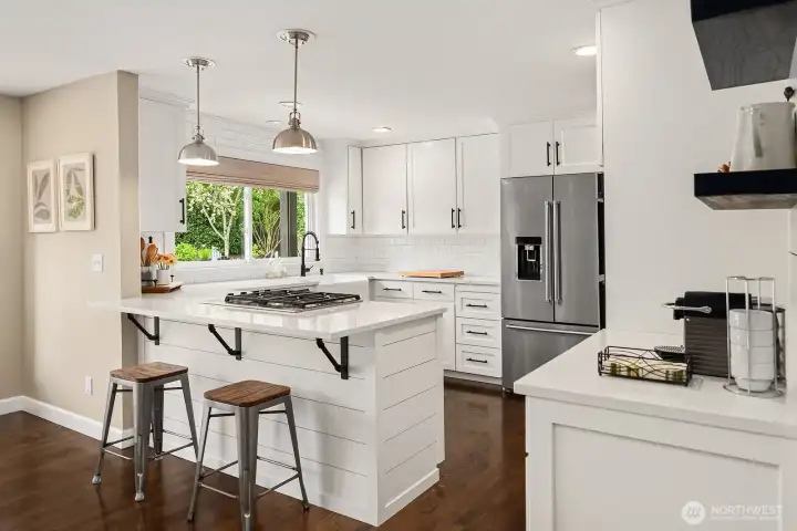 Crisp white cabinetry, all-new stainless appliances, and rich hardwood floors combine in this beautifully appointed kitchen, where pendant lighting and a welcoming island make it as stylish as it is functional.