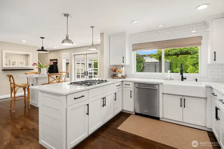 The kitchen's expansive island anchors the space beautifully, offering generous prep space and casual seating while the sun-drenched eating nook just beyond provides the perfect spot for everyday dining.