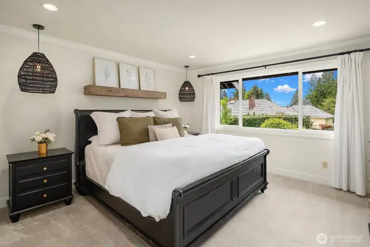 The spacious primary suite is a serene retreat, bathed in natural light from large windows framing treetop views, with ample room for a full bedroom set and a generous walk-in closet just steps away.