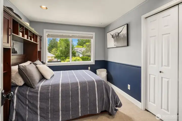 One of three additional bedrooms offers a cozy and characterful retreat, with built-in shelving, treetop views, and plenty of natural light — reflecting the warmth and quality found throughout this exceptional home.