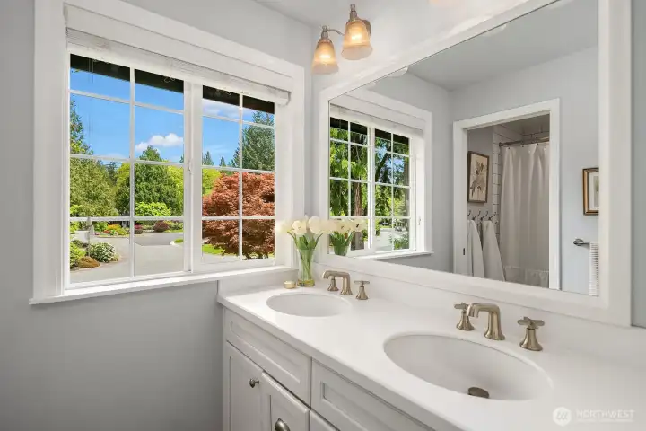 The beautifully appointed full bath shared by the three additional bedrooms features a dual vanity, elegant fixtures, and a sun-filled window with lovely garden views — stylish and functional in equal measure.