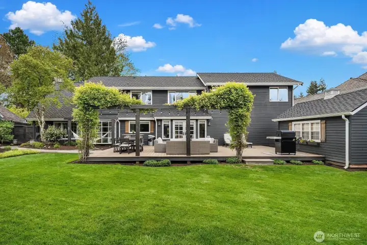 The fully fenced backyard is a private, peaceful retreat showcasing lush professional landscaping, a sprawling lawn, and the brand-new Trex deck — an ideal setting for entertaining, play, or simply unwinding in total seclusion.