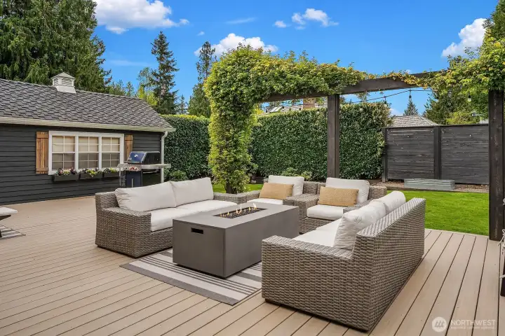 The brand-new Trex deck is an entertainer's dream, featuring a stylish outdoor lounge set and seamless flow from the kitchen's French doors — with the versatile outbuilding visible in the background, offering additional storage or flex space.