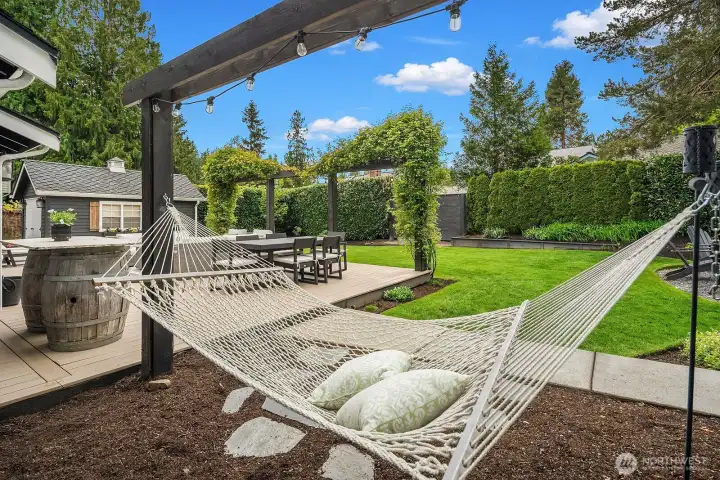 A shaded hammock area off the deck creates the ultimate backyard escape, with repaved walking paths weaving through the professionally landscaped grounds and the lush, fully fenced yard stretching out beyond.