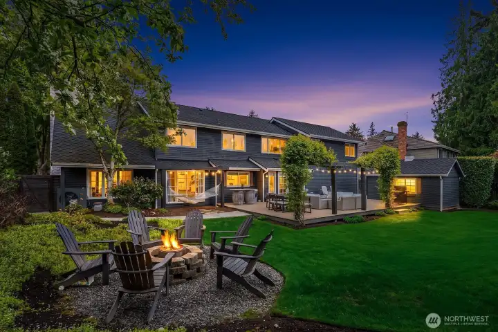 At twilight, the home's outdoor lighting illuminates the fire pit, lush landscaping, and inviting backyard in a warm, magical glow — a stunning finale that showcases just how special this property truly is.