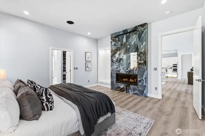 Floor to ceiling porcelain fireplace, with Cool Smart TV technology and lighted built-in shelving in main level primary bedroom.