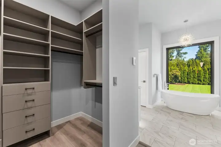 Dual side closets leading to primary bath with floor to ceiling glass porcelain tiled shower with 3 shower heads  and porcelain heated tiled floor.