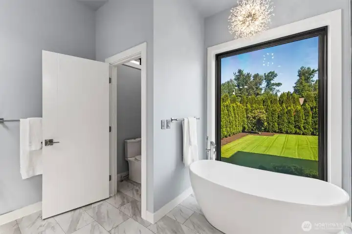 Primary bath with soaking tub and floor to ceiling feature window with privacy/clear glass option.