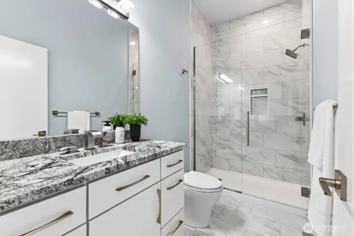 Main level guest 3/4 bath with granite surface tops and porcelain tiled floors plus glass 10-foot tall shower,  porcelain tiled throughout.