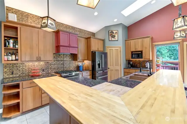 Kitchen with island cooktop, eat in counter with stools, pantry with custom shelving. Custom pendant lighting from Meyda.