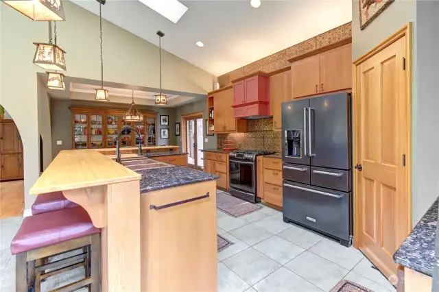 View of kitchen with custom copper sink, gas stove and tile flooring.