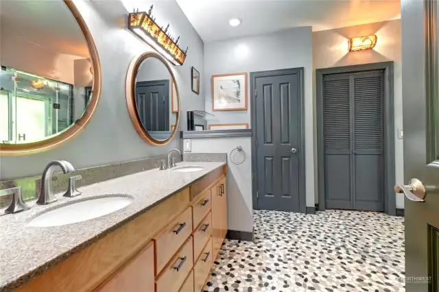 Entry way of primary bath with custom lighting, double sink and fun tile flooring.