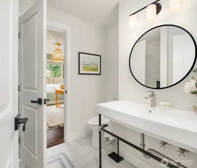 This downstairs guest bath offers a tile shower, shiny basin sink and handsome black fixtures with modern exposed plumbing features.