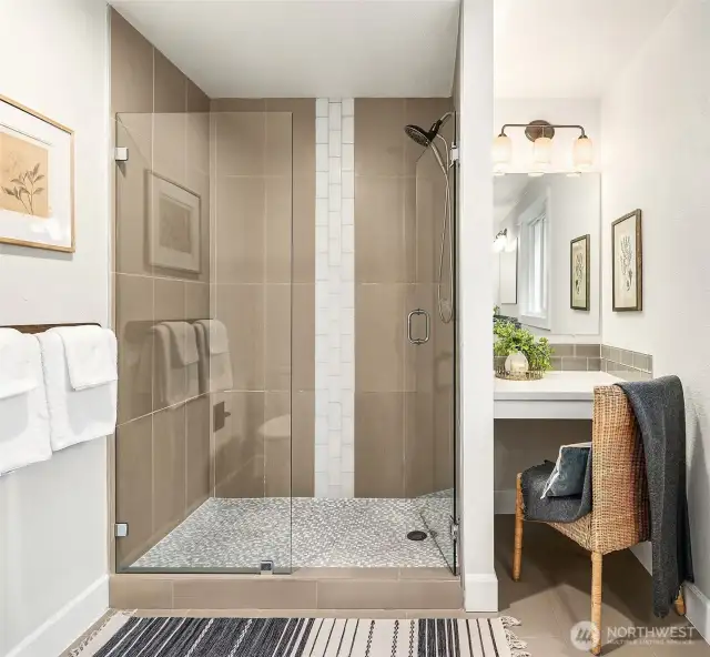 A spacious step-in shower with subway tile accent and shiny glass shower doors.