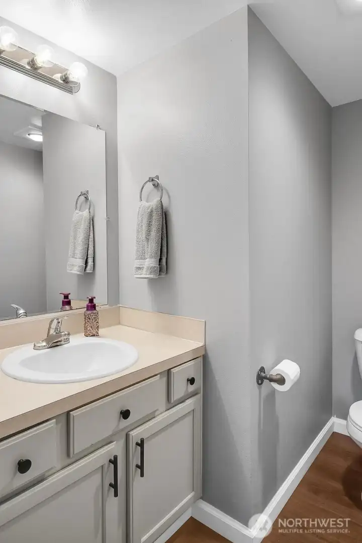 Main floor bath featuring refurbished cabinets, new flooring and fixtures. Notice how the new flooring and new baseboard trim create a stunning look.