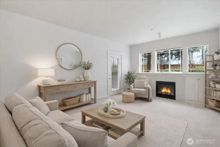 The living room has a cozy gas fireplace and big windows for natural light.  This photo has been virtually staged.