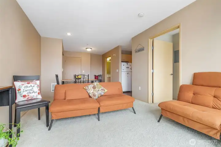 Carpeted living room with view into kitchen and entry