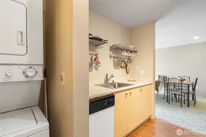 Kitchen and in-unit laundry area with dining space visible beyond