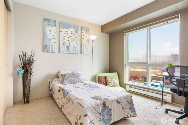 Primary bedroom with large window, natural light, and city views