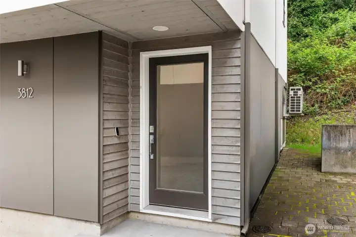 Covered entry with modern front door, exterior siding detail, and private walkway access.