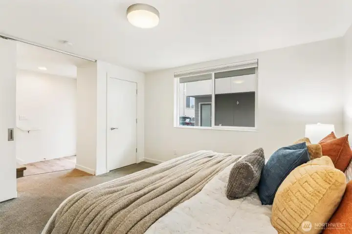 Bedroom 1 with carpet flooring, window for natural light, and adjacent bathroom access.