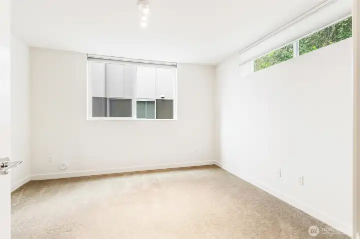 Lower-level bedroom with carpet flooring, egress window, and natural light.