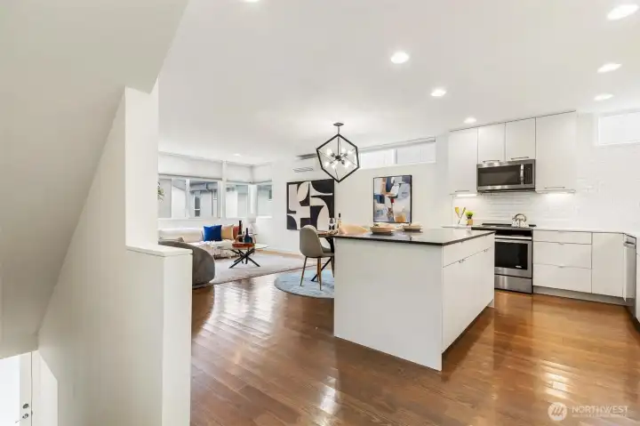 Main level open-concept layout with kitchen, dining, and living areas, featuring hardwood flooring and recessed lighting.