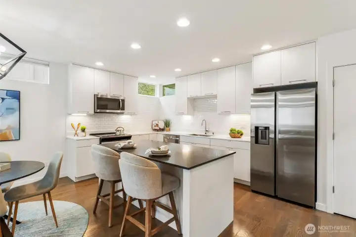 Kitchen with quartz countertops, center island seating, stainless steel appliances, and white cabinetry.