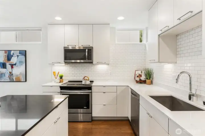 Kitchen layout showing L-shaped design with stainless steel appliances, dishwasher, and ample counter space.
