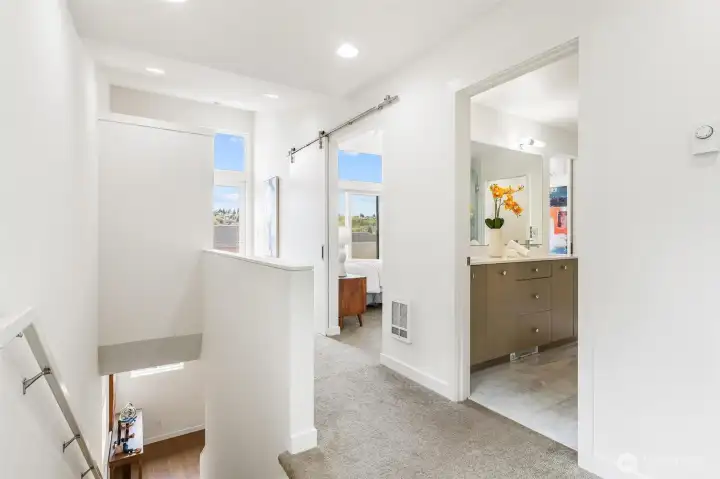 Upper level landing with access to primary suite, natural light, and multi-level layout.