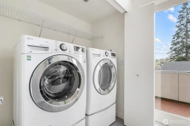 Top-floor laundry area with side-by-side washer and dryer and upper shelving for storage.