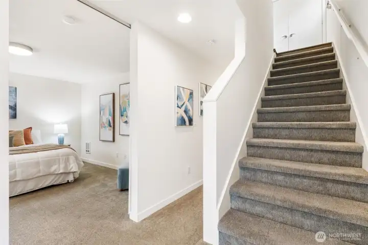 Lower-level hallway with access to 2 bedrooms a full bathroom, and staircase to the main level.