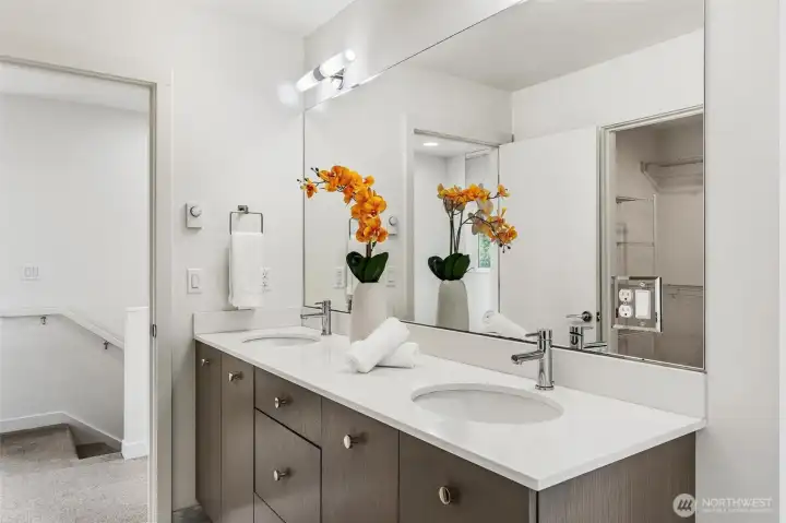 Primary bathroom vanity detail with dual sinks, storage cabinetry, and large mirror.