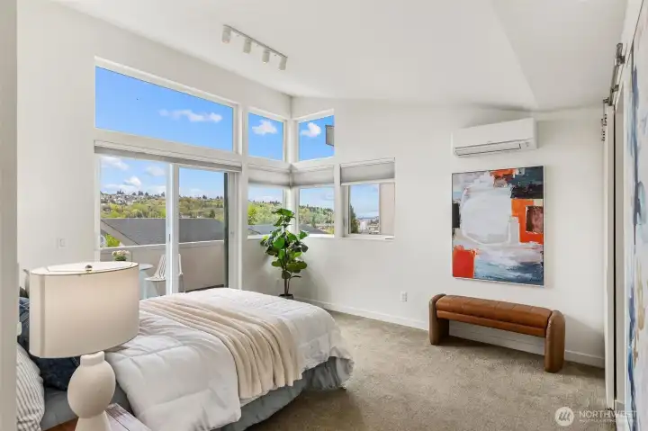 Primary bedroom with large windows, vaulted ceiling, ductless mini-split system, and territorial and city views.