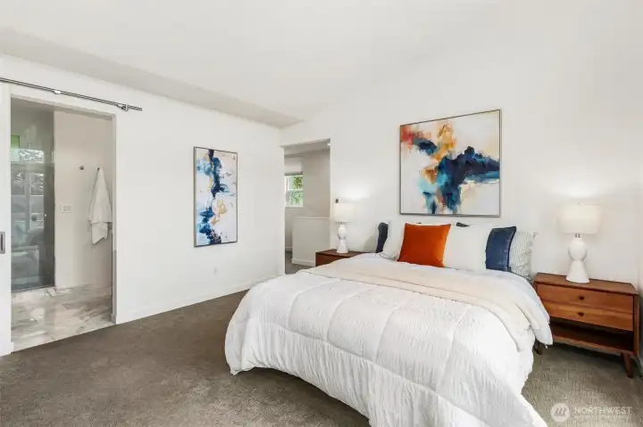 Primary bedroom with carpet flooring, adjacent bathroom access, and walk-in closet entry.