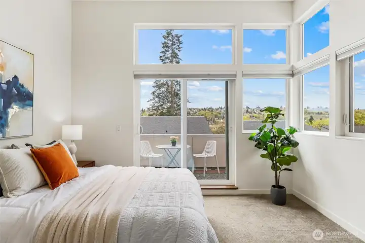 Primary bedroom with vaulted ceilings, large windows, and sliding glass door to private deck.