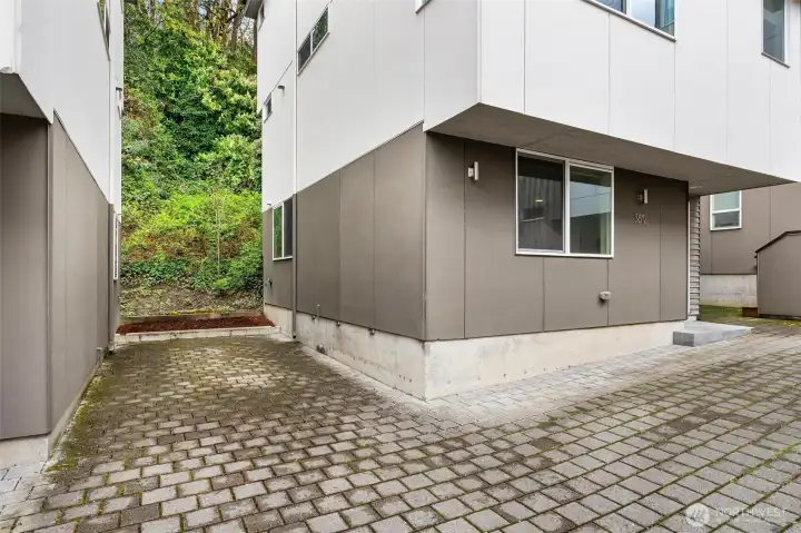 Dedicated off-street parking area with paver surface and ground-level access to home.