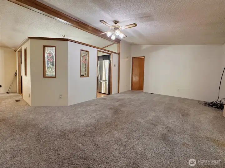 Entryway leading into living room, showing partial wall surrounding kitchen Entryway leading into living room, showing partial wall surrounding kitchen