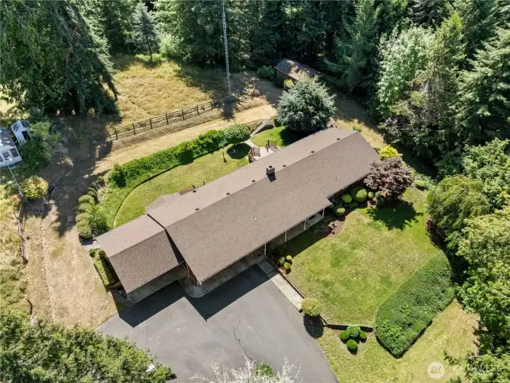 Bird's-eye view of the home and the established yard and paved driveway.