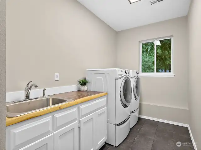 Freshly remodeled laundry room with live edge countertop, stainless sink & LVT floors. Whirlpool steam washer/dryer included