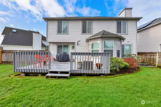 View of the back of the house. Easy care landscaping. Greenery borders the deck area.