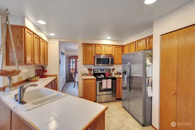 Cooks delight kitchen has gleaming tile counter tops, oak cabinets and drawers, ample storage and prep space areas. Walk in pantry. Newer stainless-steel appliances for your convenience.