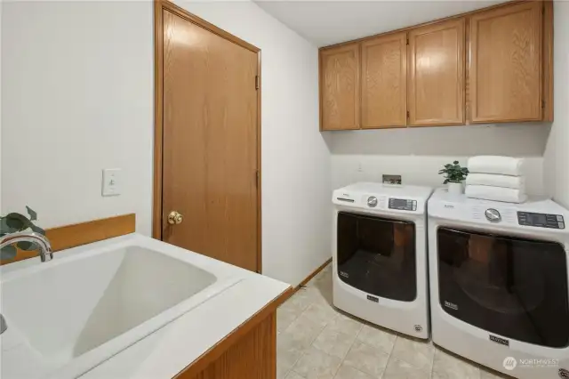 The laundry room features a side-by-side washer and dryer, cabinet storage and a handy utility sink.