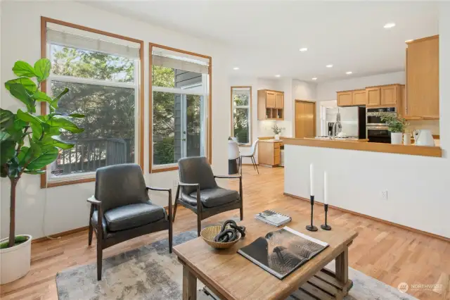 The family room features a cozy gas fireplace and light-filled windows overlooking an entertainer’s composite deck, patio, and lush trees.