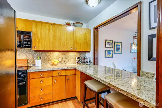 Wood cabinets, quartz counters, room above the cabinets for treasure, and bar seating facing the water view.