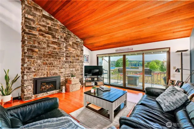 The beautiful propane fireplace has a floor to ceiling stone wall that meets the vaulted wood ceiling.