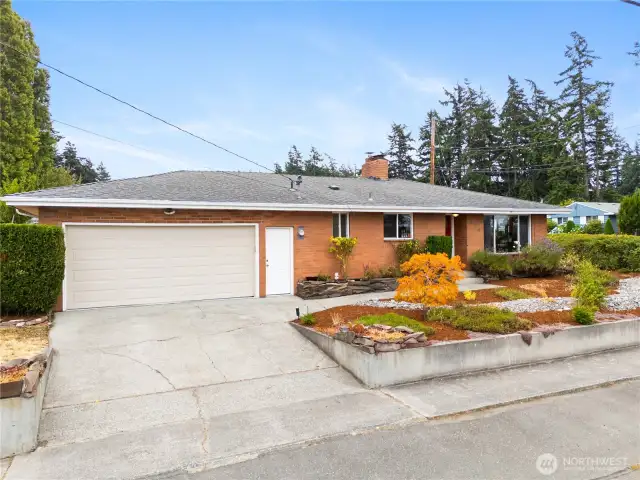 Two car garage, neighborhood sidewalk, and low maintenance front yard landscaping with clean curb appeal.