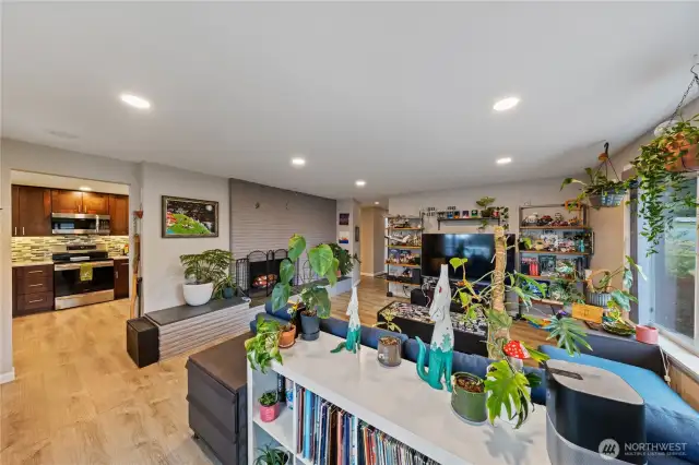 Spacious living room with large windows, abundant natural light, and a cozy wood-burning fireplace.