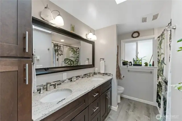 Spacious updated hall full bathroom with dual sinks, durable quartz counters, and an overhead skylight.