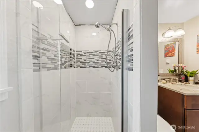 Updated 3/4 bath features glass door and modern tiles.